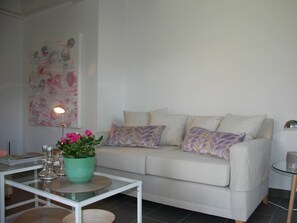 Un salon avec un canapé, une table basse, une lampe et un tableau au mur.