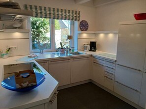 Une cuisine moderne équipée d’un lave-vaisselle encastré, d’un évier et d’une fenêtre donnant sur un espace verdoyant.