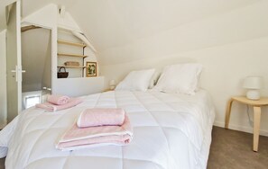 Une chambre à coucher avec un lit, une table de chevet, une lampe et une étagère sur laquelle se trouvent un tableau et un panier.