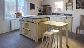 A kitchen with a central island, a stove, and a window with a view of trees. - Beauregard Guesthouse, just a stone's throw from the Loire River (Brissac Loire Aubance)