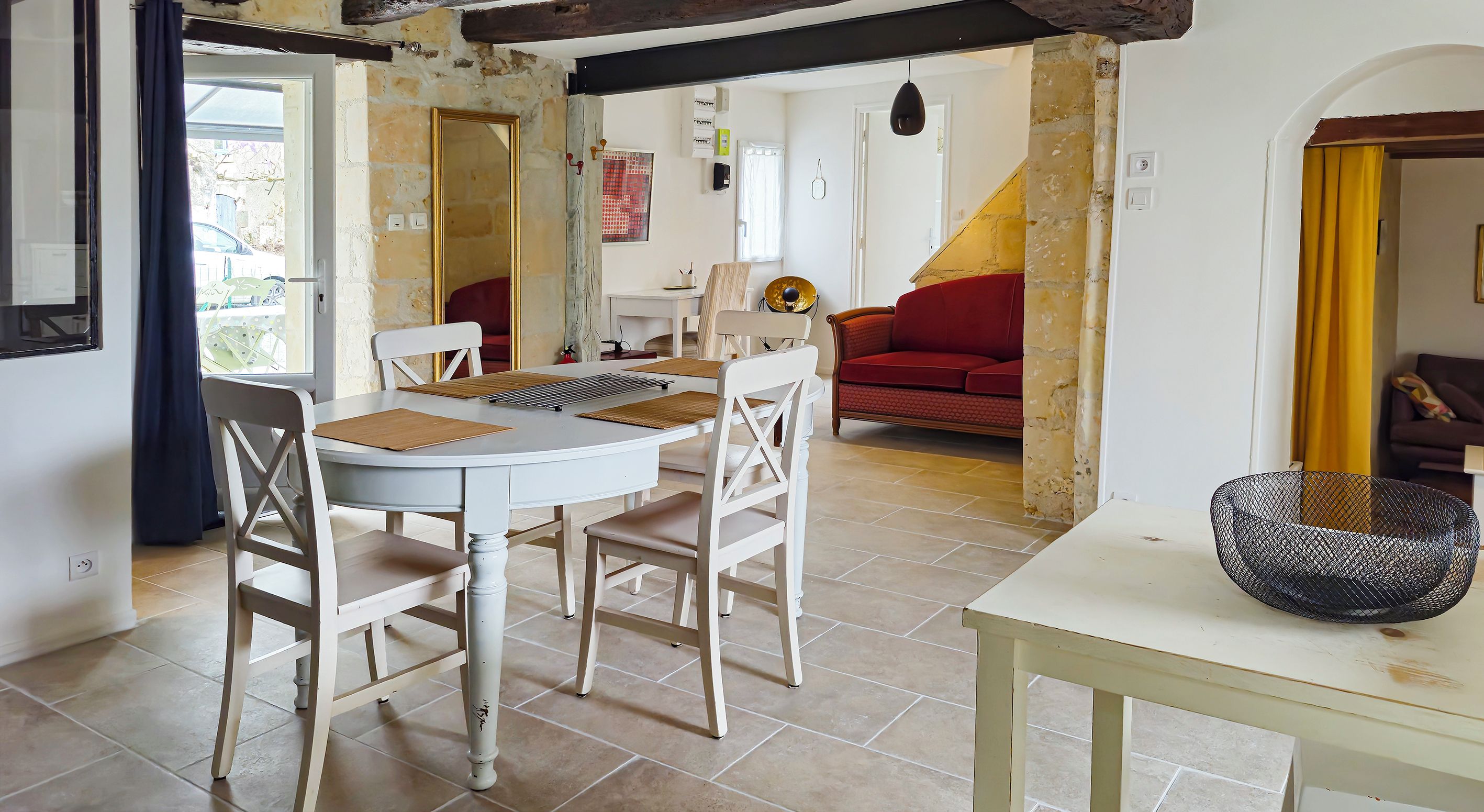 Un coin repas avec une table ronde, des chaises blanches et un canapé rouge en arrière-plan.