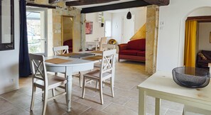 Un coin repas avec une table ronde, des chaises blanches et un canapé rouge en arrière-plan.