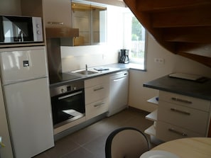 A compact kitchen with a refrigerator, oven, microwave, sink, and a coffee maker. - Norman Longhouse with Garden and Pets Allowed (La Hague)