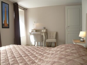Une chambre avec un grand lit, un bureau, une chaise et une porte.