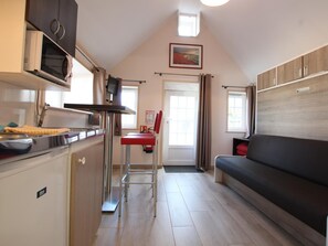 A compact kitchen with a microwave, stove, and a small dining area. - Norman Longhouse with Garden and Pets Allowed (La Hague)