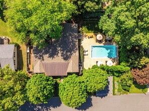 Vue aérienne d’une propriété résidentielle dotée d’une piscine, d’un patio couvert et d’un espace verdoyant.