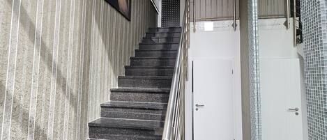 Una escalera con barandilla de metal que lleva a una puerta blanca.
