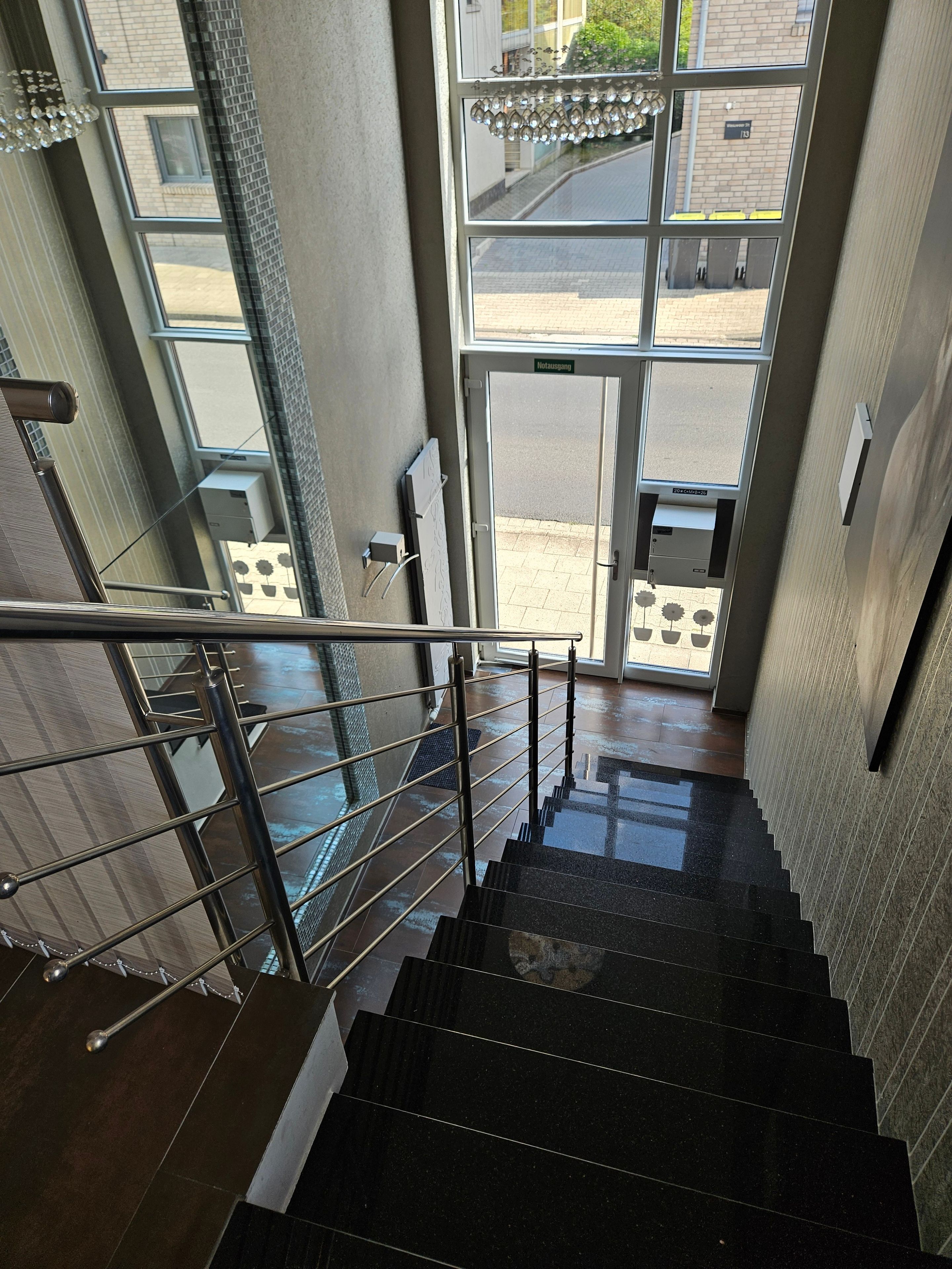 Una escalera con barandilla metálica que lleva a una entrada con puertas de cristal.