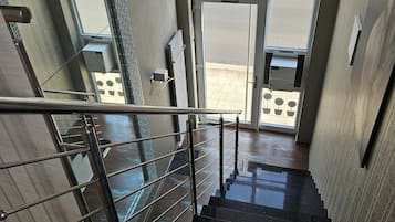 Una escalera con barandilla metálica que lleva a una entrada con puertas de cristal.