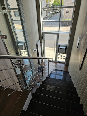Eine Treppe mit Metallgeländer führt zu einem Eingang mit Glastüren.