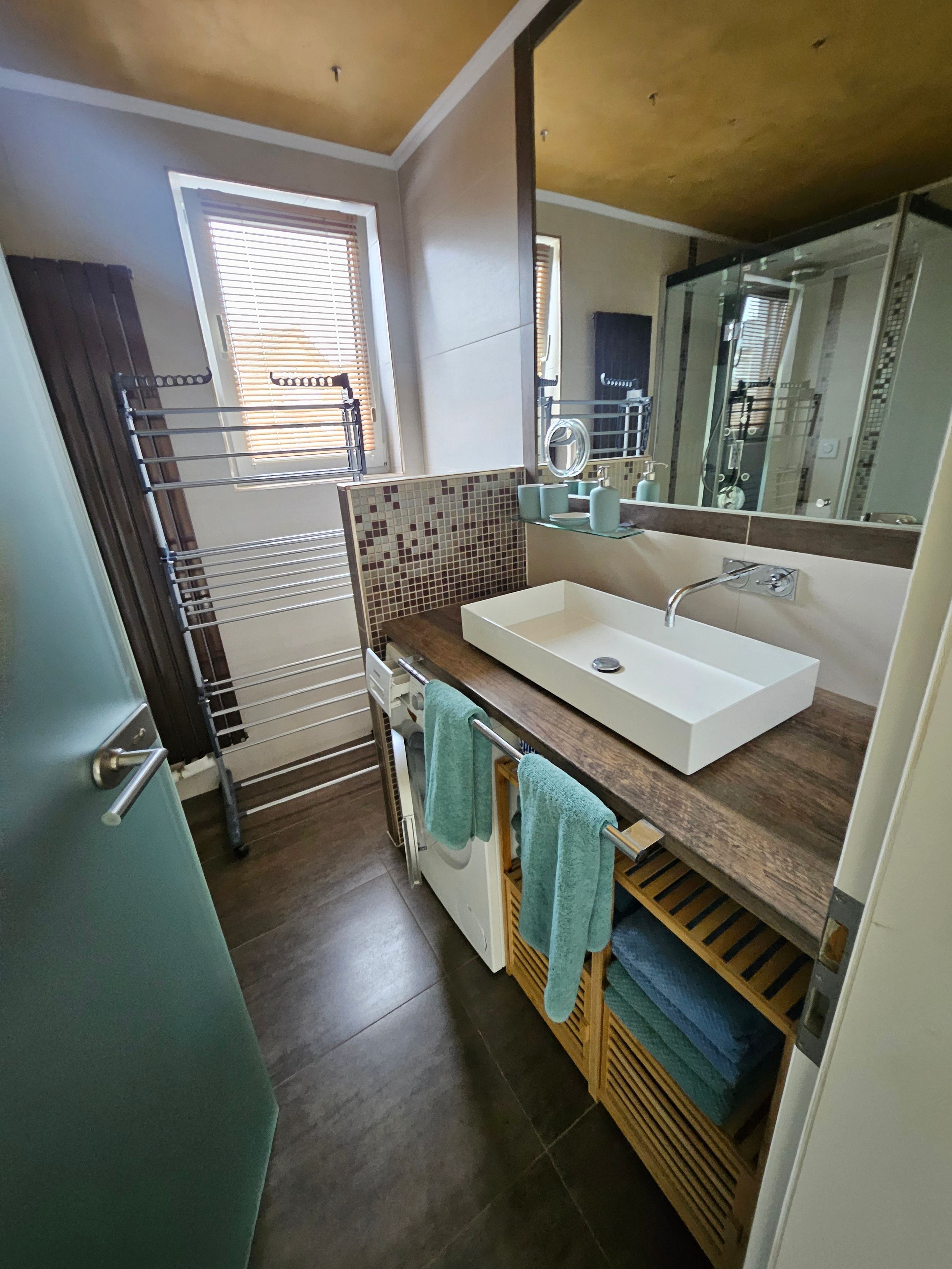 A modern bathroom with a white sink, a mirror, and a towel rack.