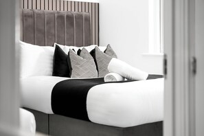 Ein Bett mit Kopfteil, mehreren Kissen und einer Decke.