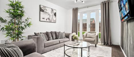 A modern living room with a grey sofa, a round coffee table, and a large plant.