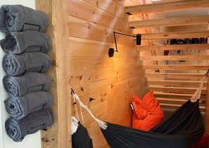 Ein Holzblock-Interieur mit einer Hängematte, einem Schuhregal und einem Wandhandtuchhalter.