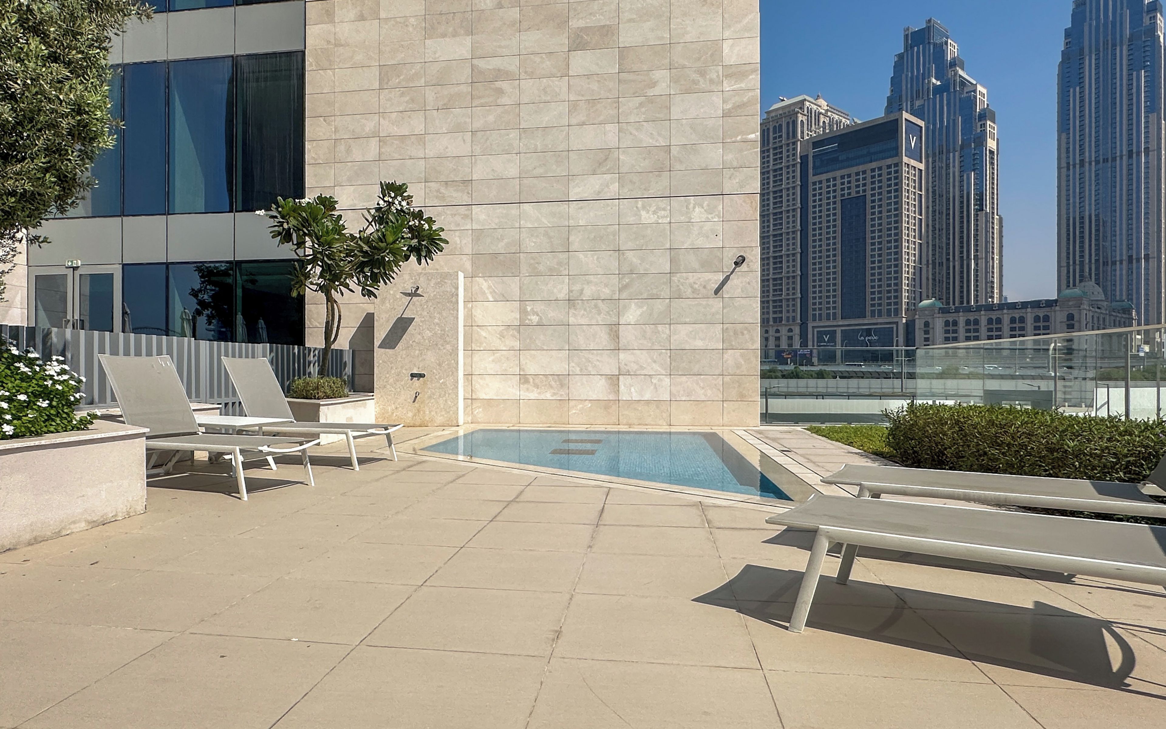 A rooftop pool area with lounge chairs and a view of tall buildings.