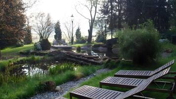 A serene outdoor area with a pond, wooden lounge chairs, and a seating area with benches.