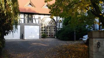 A building with a large arched window, a garage, and a driveway with fallen leaves.