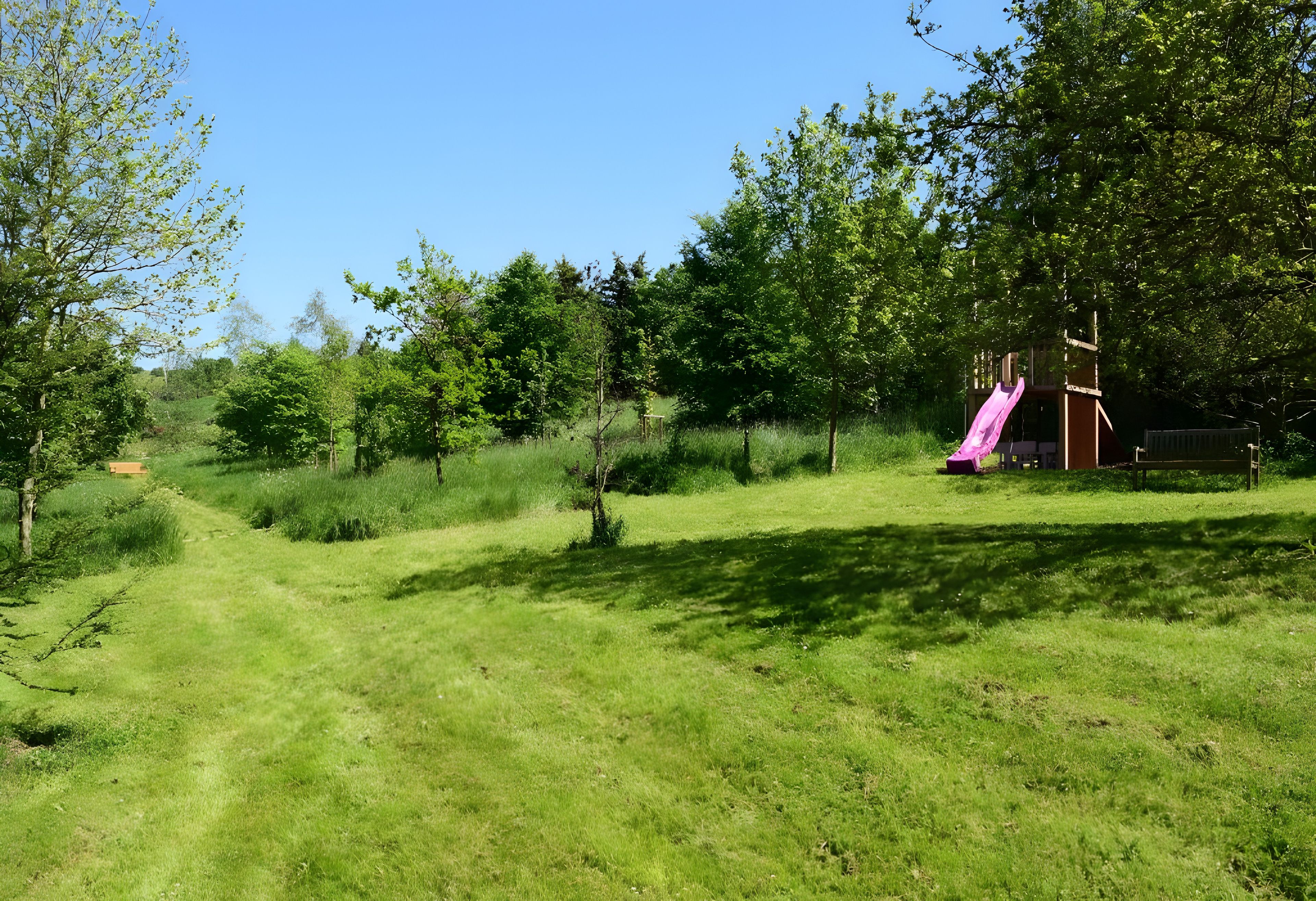 Ein grünes Areal im Freien mit einem Spielplatz, der eine Rutsche bietet.