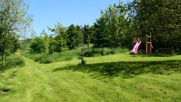 Ein grünes Areal im Freien mit einem Spielplatz, der eine Rutsche bietet.