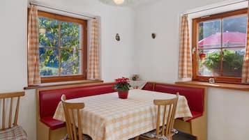 A dining area with a table set for two, red cushioned benches, and a potted plant on the table.