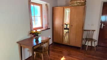 Een kamer met een houten tafel, twee stoelen, een kast, een raam met gordijnen en een houten vloer.