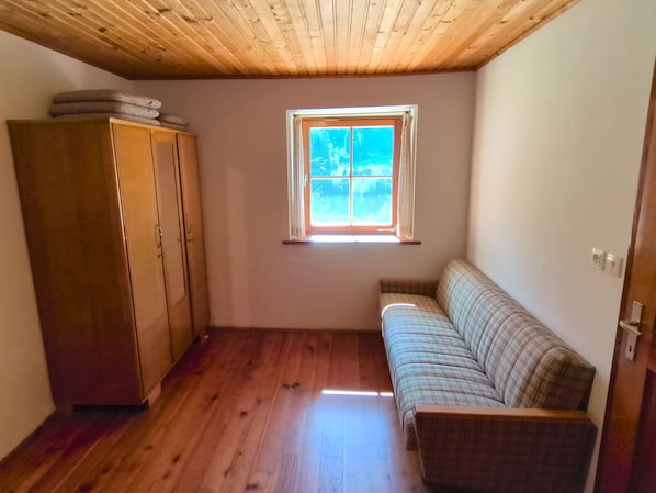 A room with a wooden ceiling, a window, a sofa, and a wardrobe. - Apartment 'Rosengarten Mitterbirbach' with Mountain View, Private Terrace and Wi-Fi (Sankt Pankraz)
