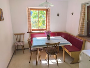 A dining area with a table, chairs, a bench, and a window with curtains. - Apartment 'Rosengarten Mitterbirbach' with Mountain View, Private Terrace and Wi-Fi (Sankt Pankraz)
