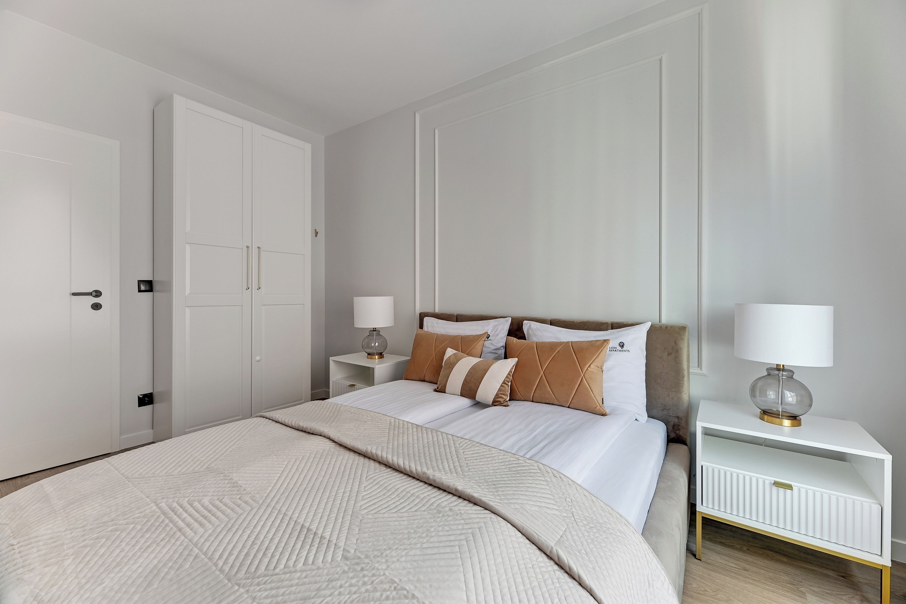 A hotel room with a large bed, two bedside tables with lamps, a wardrobe, and a radiator.