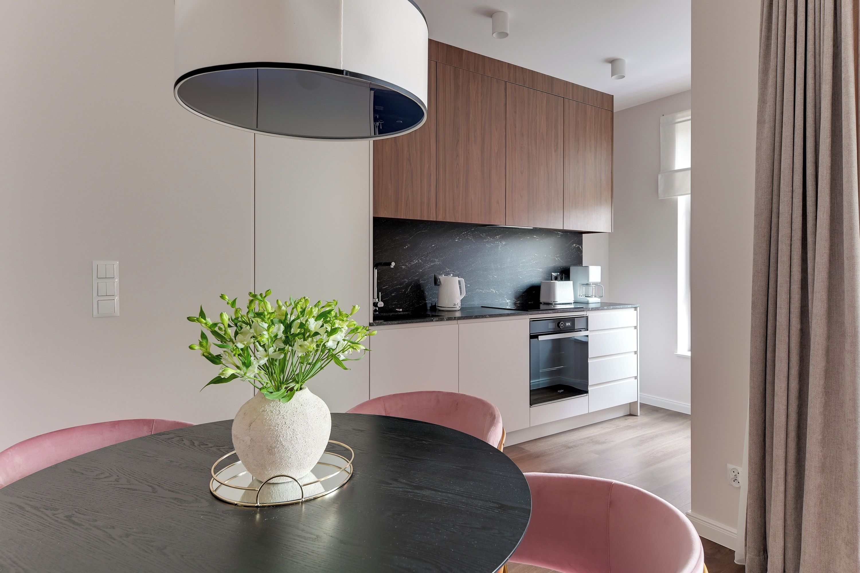 A modern kitchen with wooden cabinets, a black countertop, and a built-in oven.