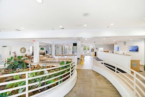 A spacious lobby with a reception desk, seating areas, and a decorative indoor garden. - Disney Days 15 Min Away With Pools and Hot Tubs (Davenport)