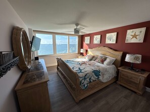 A bedroom with a bed, bedside tables, a desk, a mirror, and artwork on the walls. - Direct Bay Views - Private Balcony Pool Hot Tub (St. Petersburg)
