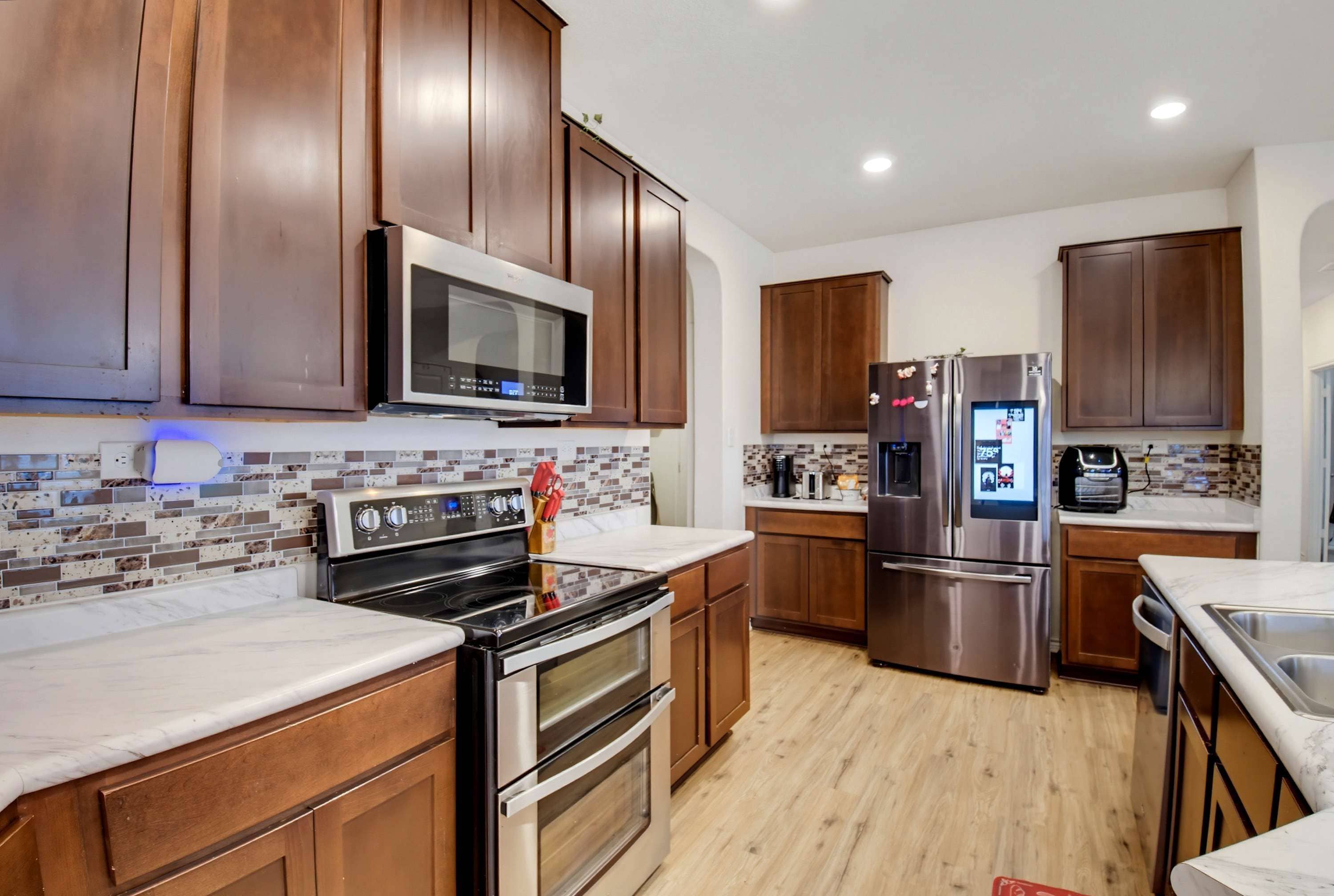 A modern kitchen with wooden cabinets, a stainless steel refrigerator, a microwave, and a stove.