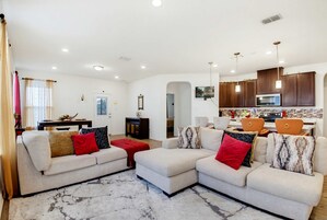 A modern living room with two sofas, a dining area, and a kitchen.