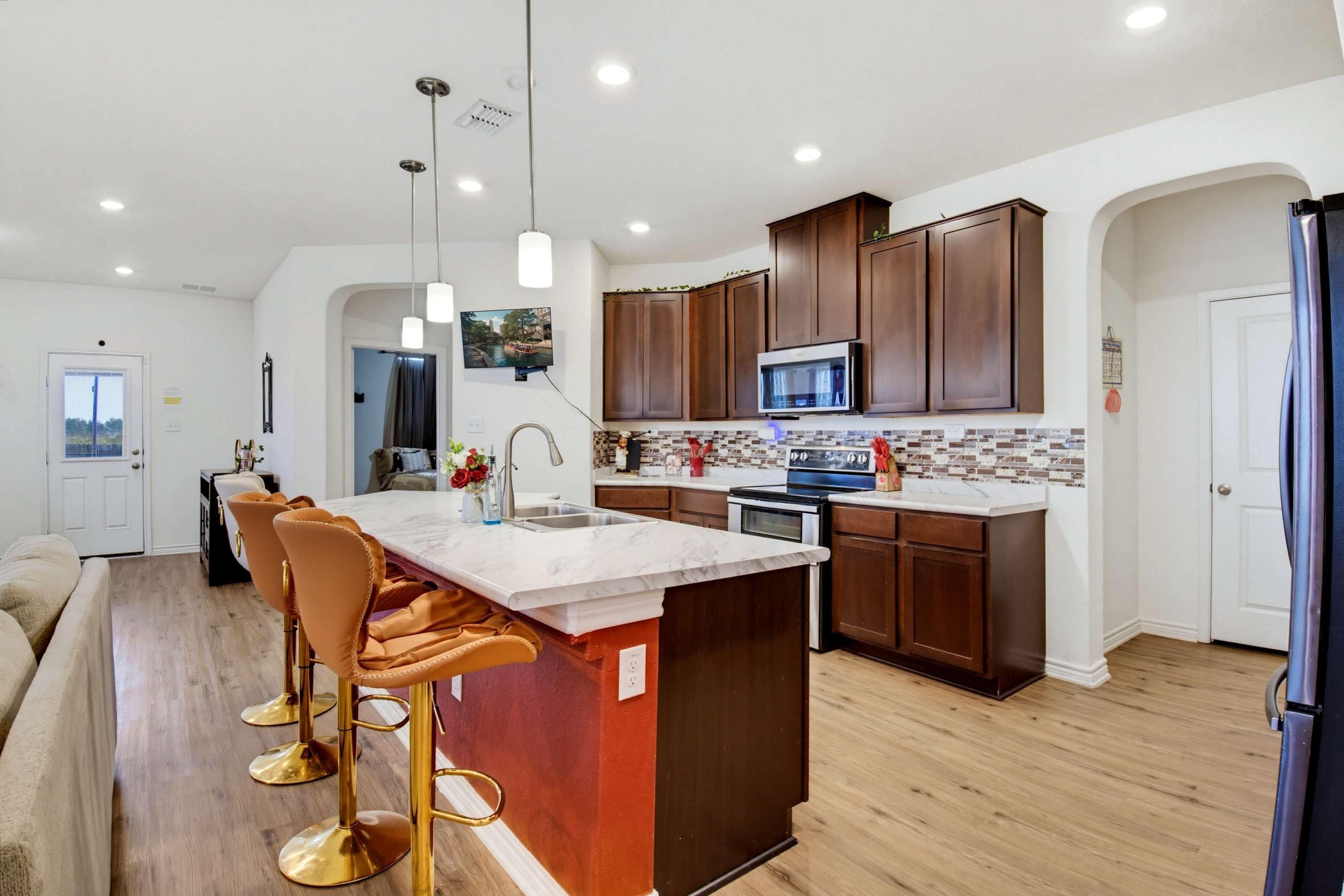 A modern kitchen with a central island, stainless steel appliances, and wooden cabinets.