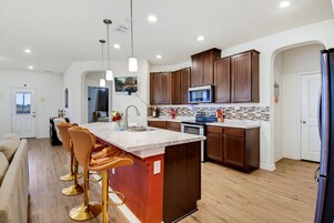 A modern kitchen with a central island, stainless steel appliances, and wooden cabinets.