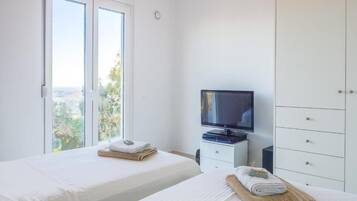 A hotel room with two beds, a television, and a wardrobe.