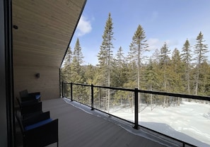 A wooden deck with a railing overlooking a snowy forest. - La Tanière de l'Ours BJÖRN HÎ, Refuge & Réconfort (Saint-Côme)