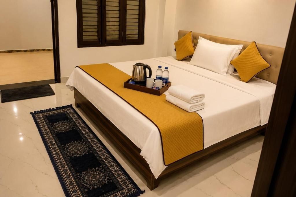 A hotel room with a bed, a tray with toiletries, and a patterned rug.