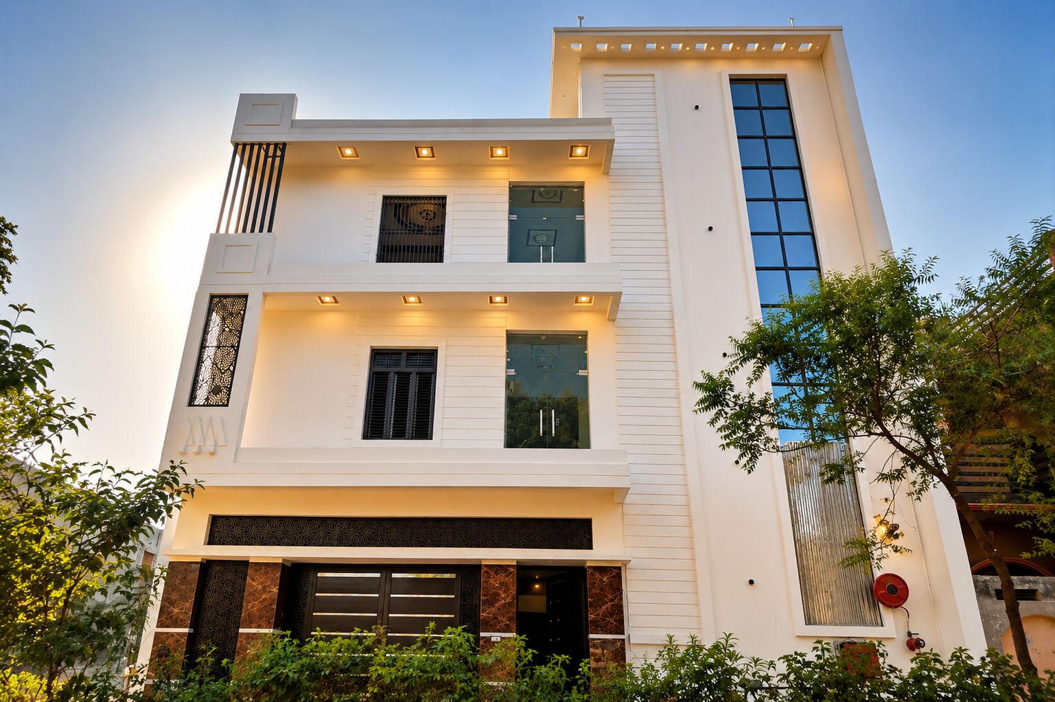 A modern two-story building with a flat roof, large windows, and a garage entrance.