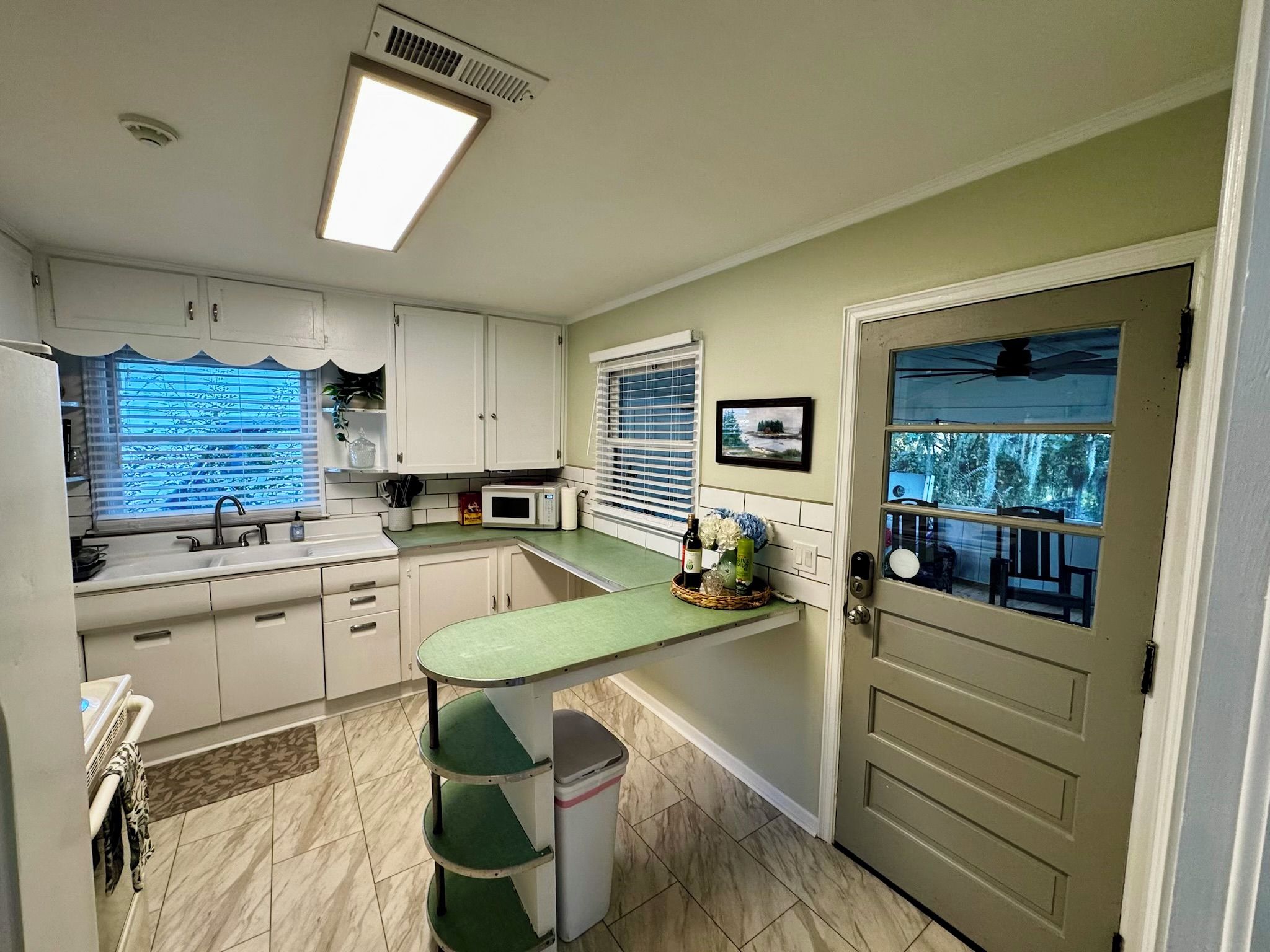 A compact kitchen with a microwave, sink, and a small dining area.