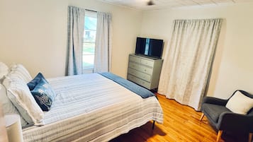 Ein Schlafzimmer mit einem Bett, einem Schminktisch, einem Fernseher und einem Deckenventilator.
