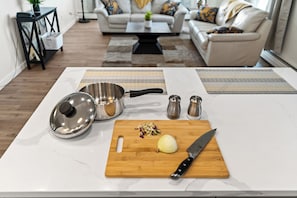 A kitchen counter with a cutting board, a knife, a pot, and two salt shakers. - 2-bedroom, downtown 16th floor, river-view, apartment with AC, gym and parking (Saskatoon)