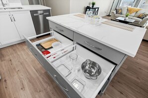 Eine moderne Küche mit weißen Schränken, einem integrierten Geschirrspüler und einer Arbeitsplatte mit Wasserspender und Korb.