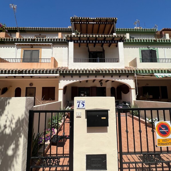 A multi-story building with a gated entrance, a mailbox, and a sign indicating a permanent vehicle parking restriction. - Casa Resort Mi Alcazar by Rental Hero (Alcazares, Los)