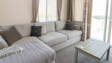 A living room with a sofa, a coffee table, and curtains.