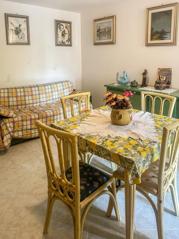Un coin repas avec une table dressée pour quatre personnes, entourée de chaises en osier.