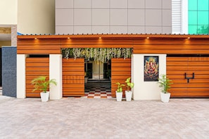 A modern building facade with a wooden panel design, a checkered entrance, and potted plants. - Collection O RPS More (Danapur)