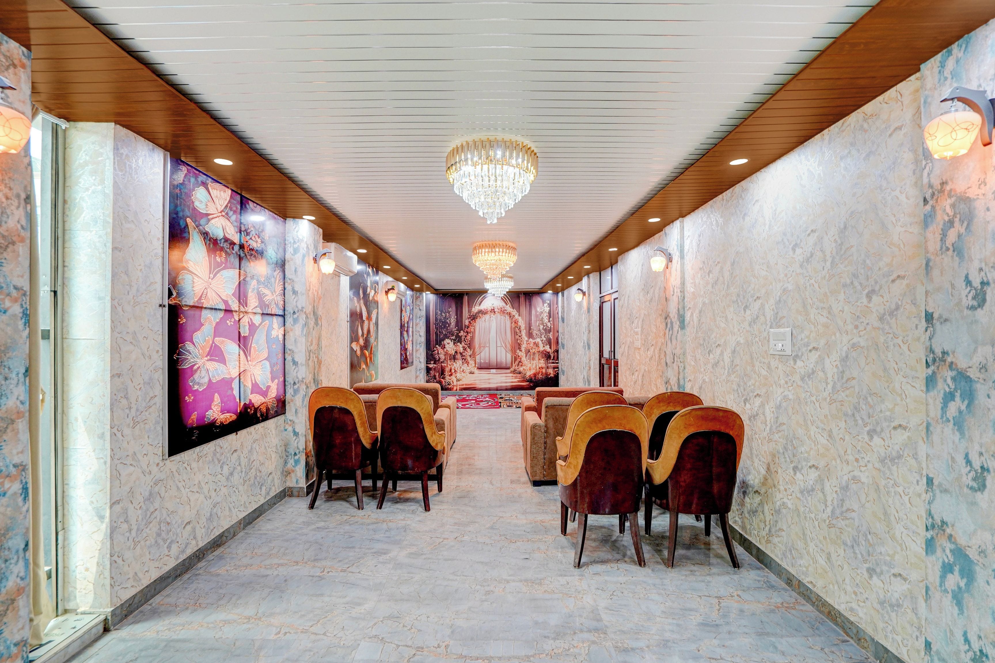 Un hall de hotel con suelo de mármol, techo de paneles de madera y una araña. Hay varias sillas y un mostrador de recepción.