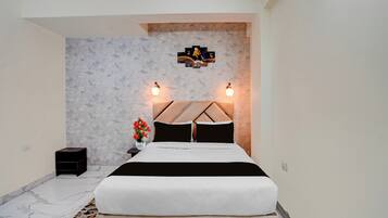 Un dormitorio con cama, mesita de noche, un jarrón con flores y una lámpara de pared.