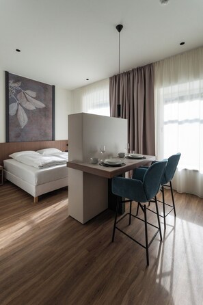 A modern hotel room with a bed, a desk, two chairs, and a large window with curtains. - Aparthotel Krone 1895 (Klausen)
